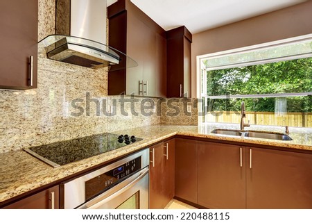 Modern kitchen room with matte brown cabinets, shiny granite tops, steel stove with hood and granite back splash