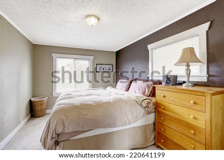 Bedroom with queen size comfortable bed. Contrast color wall in dark brown and light grey colors