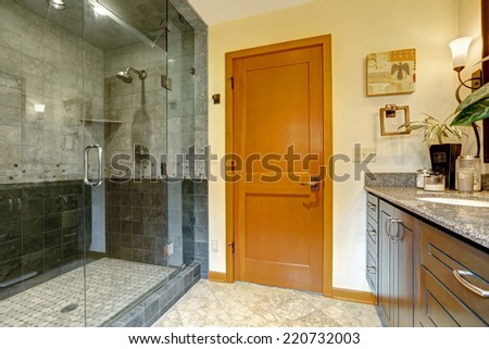 Modern bathroom interior with glass door shower and tile wall trim. Bathroom with bright orange door