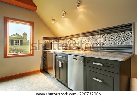 Dark green kitchen cabinets with back splash trim, steel appliances in small room with vaulted ceiling
