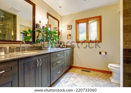 Modern bathroom interior with big cabinet and two mirrors in soft ivory room with tile floor and window
