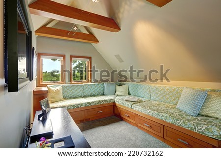 Upstairs room with vaulted ceiling and beams. Cozy sitting area with pillows . Room has tv