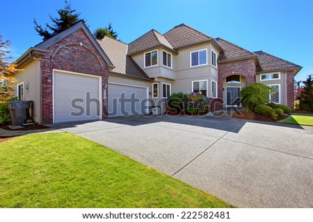 Luxury house with tile roof and brick trim. View of garage with driveway