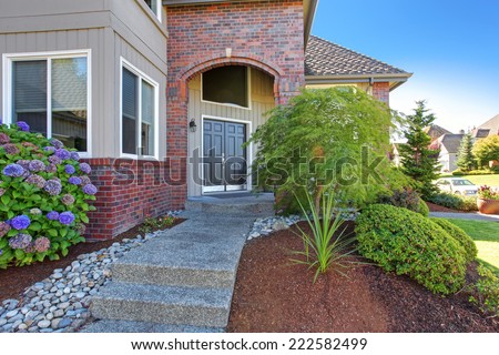 Big luxury house with tile roof and brick trim. View of entrance porch with brick trim
