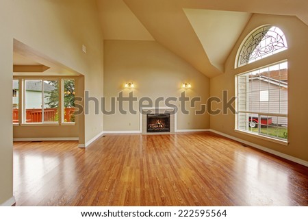 Spacious living room with high ceiling, big arch window, fireplace and new hardwood floor in empty new house