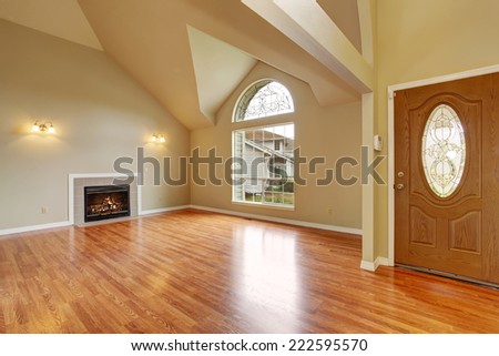 Spacious living room with high ceiling, big arch window, fireplace and new hardwood floor in empty new house.