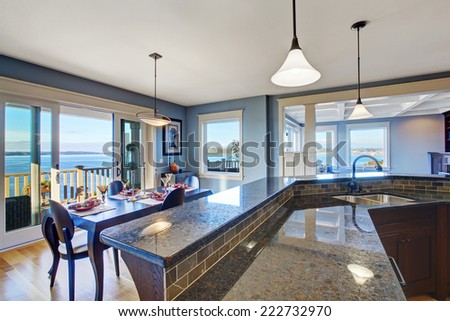 Luxury kitchen with dark brown cabinets and granite top. Kitchen has dining area and sliding doors to walkout deck