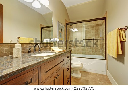 Bathroom interior with screened bath tub, wooden vanity cabinet with drawers and granite top