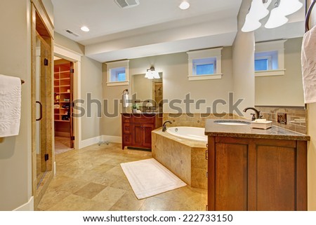 Luxury bathroom with granite tile trim. Spacious bathroom with corner bath tub, two vanity cabinets and walk in closet