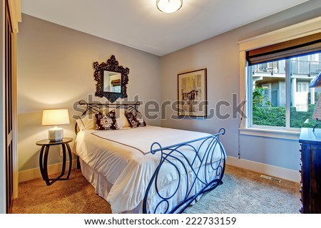 Cozy bedroom with soft brown carpet floor and iron frame bed