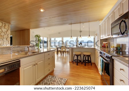 House interior. Kitchen room with paneled ceiling, white cabinets with granite tops. View of bright dining area with walkout deck