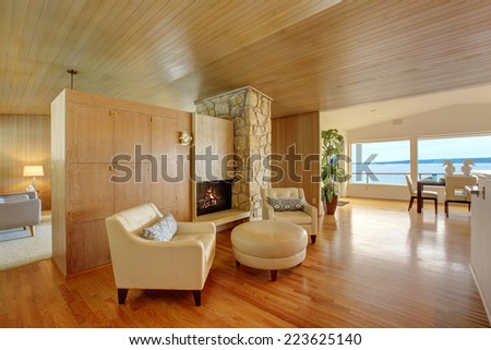 Luxury house interior. Sitting area with leather armchairs and leather ottoman. Cabinet with fireplace and rock wall trim