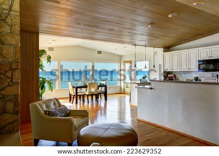 Luxury house interior. Sitting area with leather armchairs and leather ottoman. View of bright dining area with glass wall