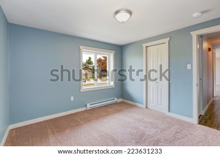 Empty small room with light blue walls and brown carpet floor. Room has closets