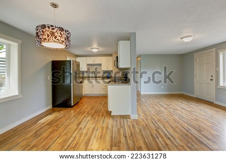Empty house interior with furnished kitchen area. Kitchen with white cabinets and refrigerator