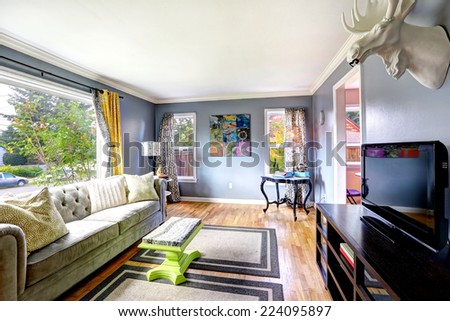Bright living room interior with large window. Furnished with sofa, cabinet with tv and table in the corner