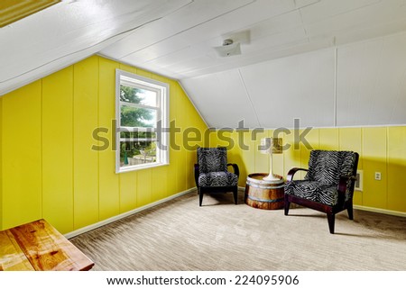 Bright yellow room with white vaulted ceiling. Sitting area with two black chairs and decorative table
