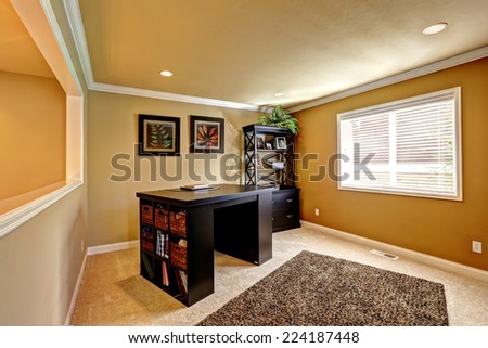 Comfortable office area with dark brown desk and cabinet. Soft brown rug on carpet floor