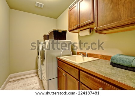Standard laundry room interior in american house. Dark brown cabinets and modern laundry appliances