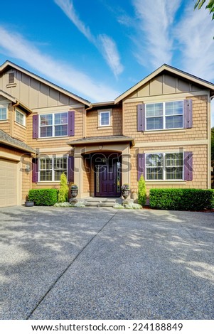 Luxury house. Clapboard siding exterior with purple elements. Entrance porch with trimmed hedges along the walls and garage with driveway