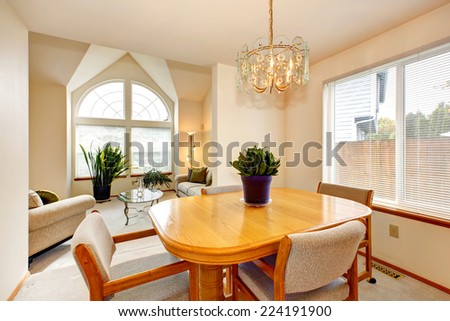 Bright dining area with maple dining table set and living room with arch window and high vaulted ceiling
