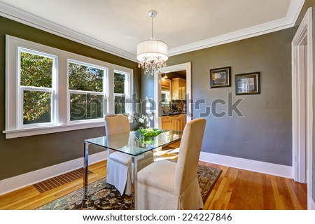 Dining room interior with dark grey walls and hardwood floor. Table with glass top and two elegant chairs