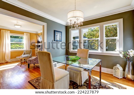 Dining room interior with dark grey walls and hardwood floor. Table with glass top and two elegant chairs