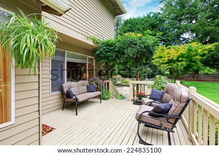 Wooden walkout deck with sitting area overlooking backyard landscape