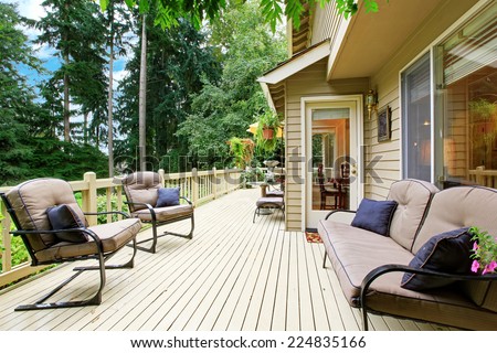 Wooden walkout deck with sitting area overlooking backyard landscape