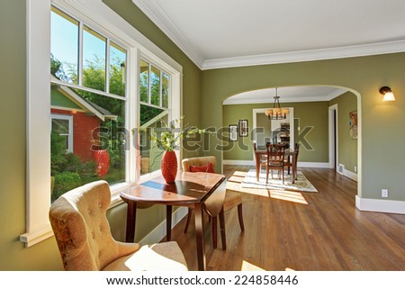 House interior with open floor plan. Sitting area by the window with table and chairs and dining room with archway