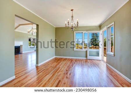 Empty dining room interior with hardwood floor, light mint walls and walkout deck