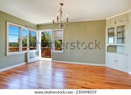 Empty dining room interior with hardwood floor, light mint walls, built-in cabinet and walkout deck
