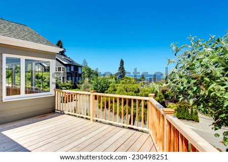 Wooden walkout deck with railings. Deck overlooking driveway and neighborhood