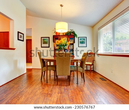 Bright dining room with vaulted ceiling and hardwood floor. Elegant dining table set with wooden cabinet and chair in the corner