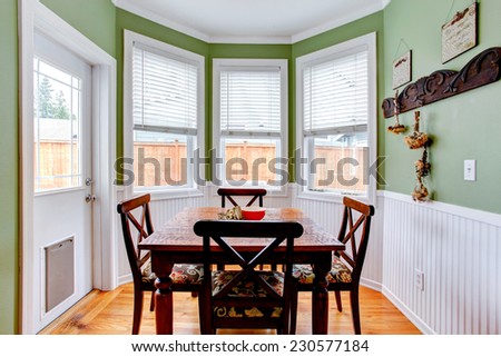 Dining room in light mint color with white trim. Dining table set . Room has exit to backyard
