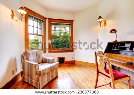 Bright room with antique desk, wooden chair and old stripped armchair.