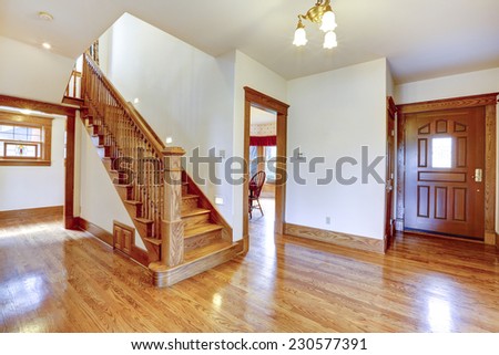 Empty house interior. Entrance hallway with new shiny hardwood floor and staircase