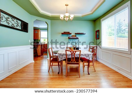 Spacious dining room in light mint color with white trim. Dining table set with crochet table cover and chairs