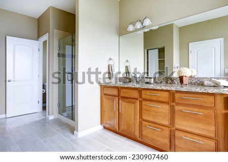 Brown vanity cabinet with granite top and mirror. Shower with glass door