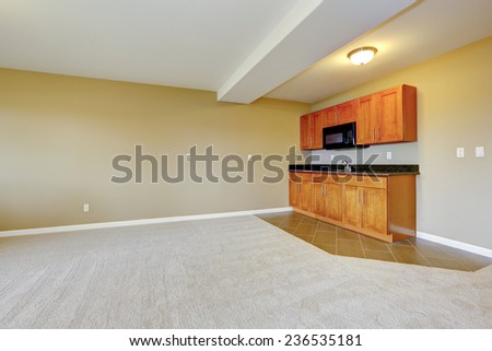 Empty house interior. Spacious dining area with kitchen cabinets. Room with two type floor covering.