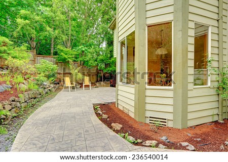 Walkout patio with sitting area and backyard leveled landscape design with stones.  Tile walkway