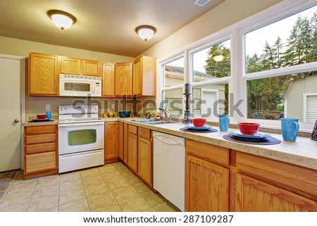 Authentic kitchen with tile floor, windows, and wooden cabinets.