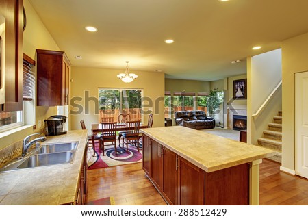 Classic kitchen with hardwood floor, island, and connected dinning room, and living room.