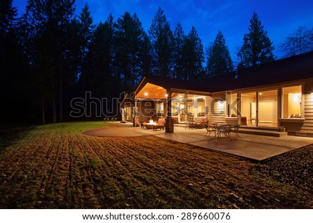 Large back yard with grass and covered patio with fire pit.