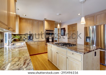 State of the art kitchen with hardwood floor, glossy counters, and stainless steel fridge.