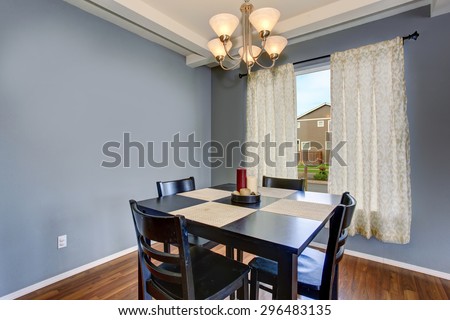 Simplistic dinning room with gray walls, and black table chair set.