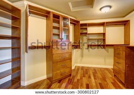 Large walk in closet with hardwood floor, also including many shelves and drawers.