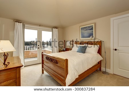 Bright bedroom with white bedding and glass door leading to balcony.