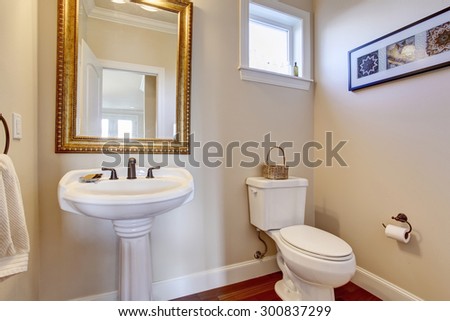 Simple bathroom with white walls, and gold framed mirror.