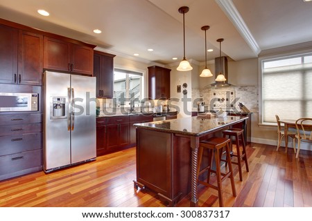 State of the art kitchen with deep stained cabinets, and stainless steel fridge.